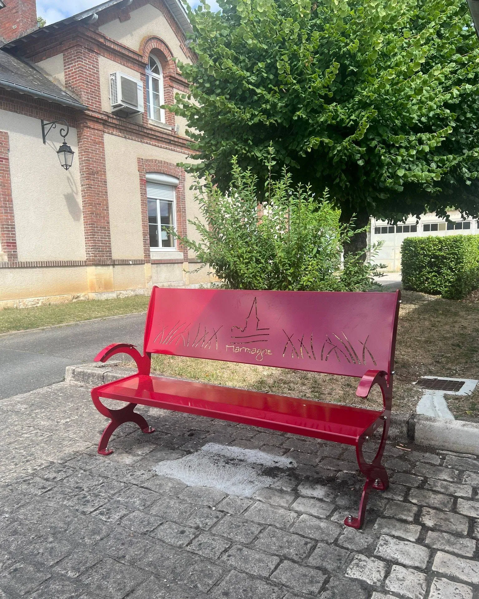 Banc public rouge personnalisé au nom de Marmagne, silhouette du clocher découpée au laser