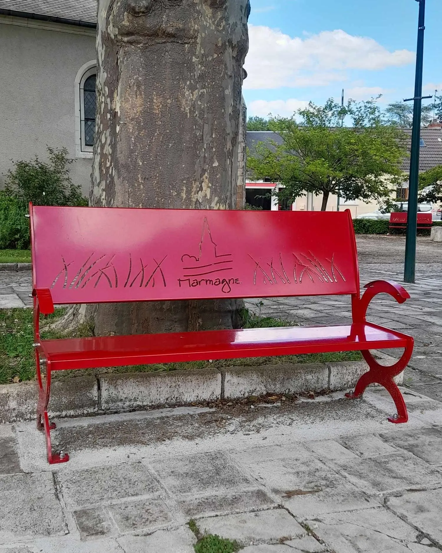 Banc public rouge personnalisé au nom de Marmagne, avec la silhouette du clocher découpée au laser