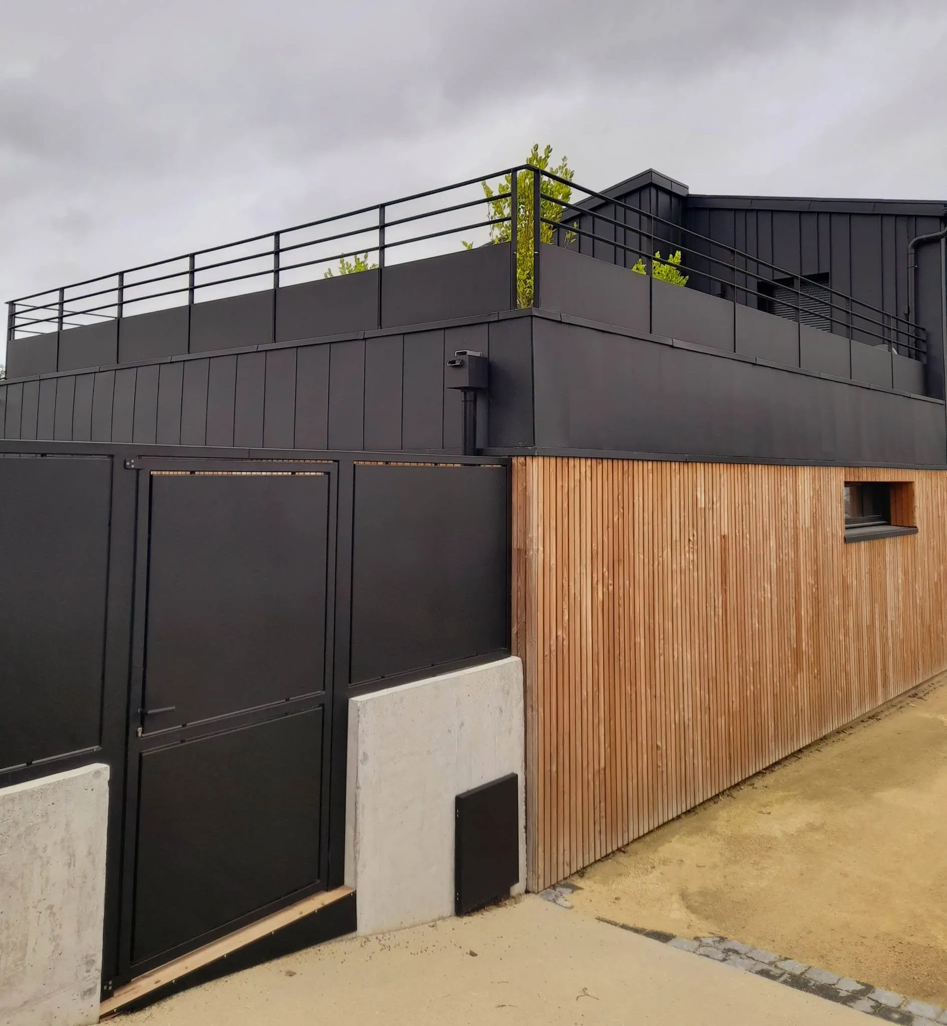 Garde-corps métalliques noirs sur terrasse et bardage acier d’un bâtiment contemporain